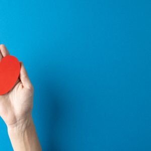 Composition of hand holding kidney on blue background