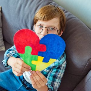 Young boy holding puzzle jigsaw, child mental health concept, world autism awareness day, autism